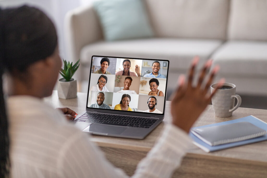 A woman participating in a virtual intensive outpatient program therapy group session from home, appearing engaged and supported by her peers on the screen.