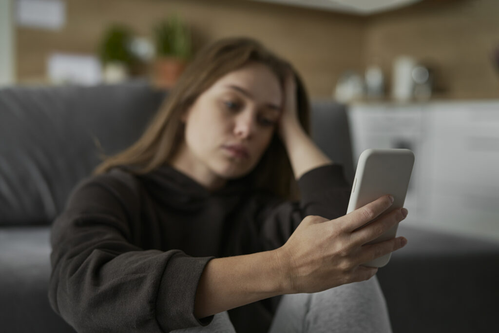 A person looking overwhelmed while scrolling through their phone, highlighting the connection between social media and mental health struggles.
