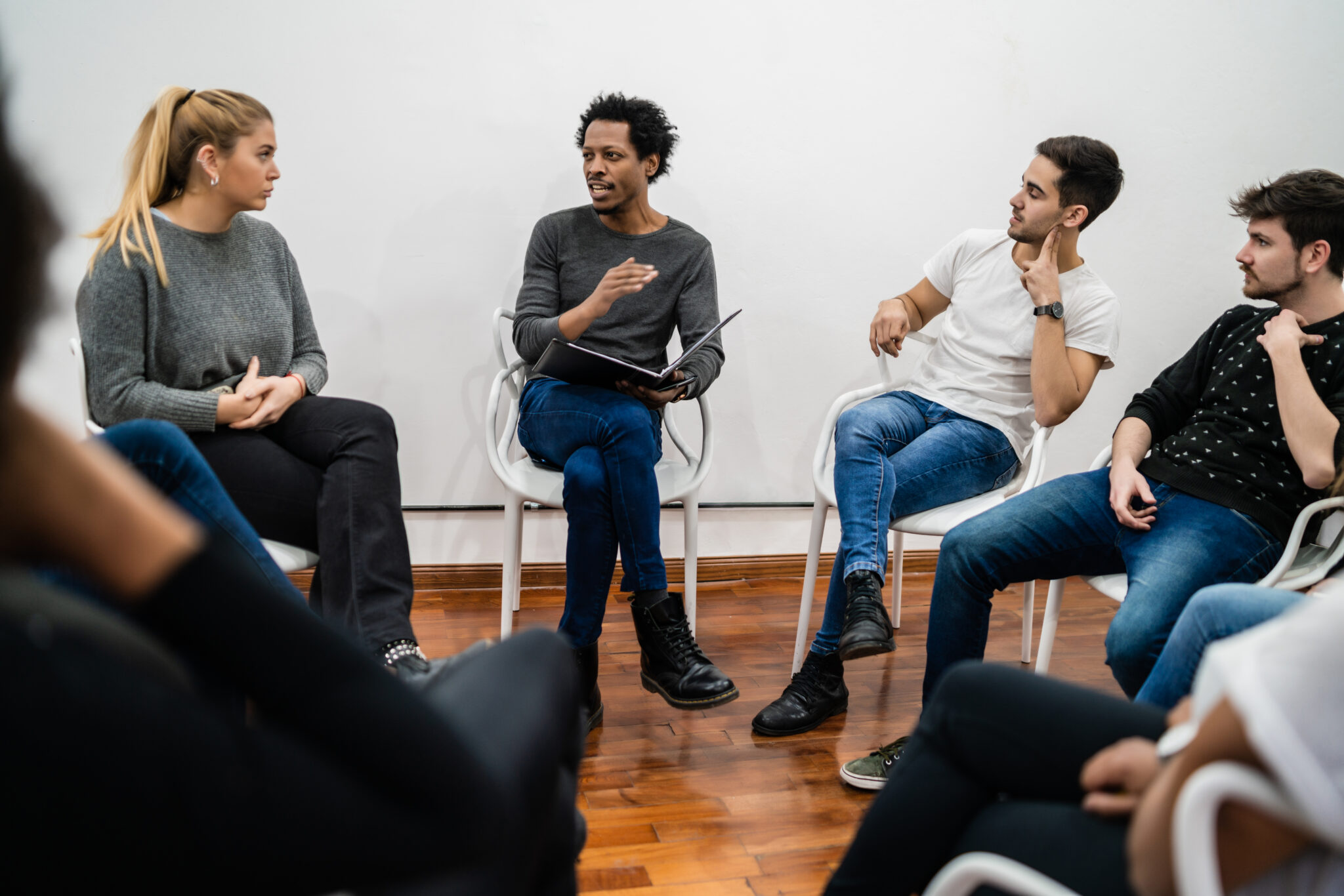 Small group therapy session in an intensive outpatient program, adults seated in a circle with a group leader