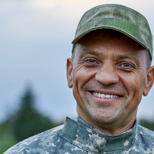 Close up face of a smiling mature soldier. Caucasian cheerful soldier outdoor.